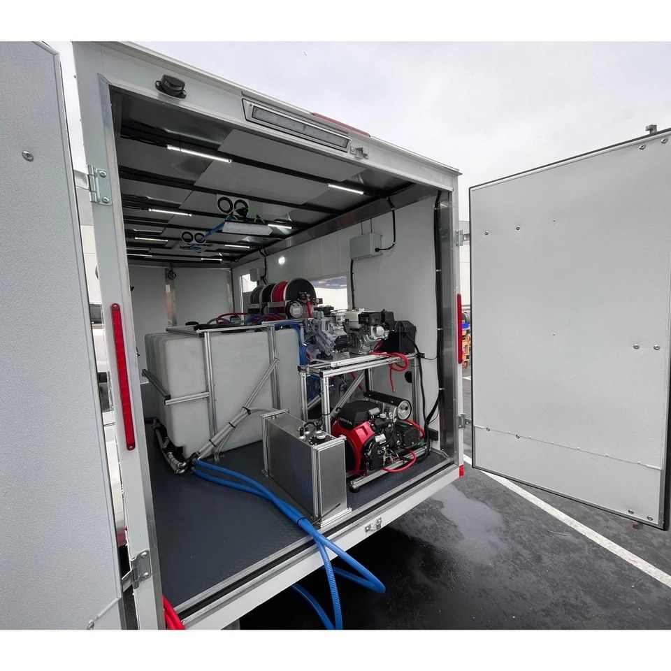 A professional pressure washing trailer setup — an enclosed trailer fitted with water tanks, pump, engine, and hose reels